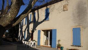 A building with blue shutters, a patio with chairs, and a tree. - Holiday Home 'Le Mas Des Fleurs' with Private Pool, Private Terrace and Wi-Fi (Avignon)