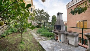 A courtyard with a stone bench, a brick building, and a palm tree. - 'Alassio Holiday' Apartment with Private Garden (Alassio)