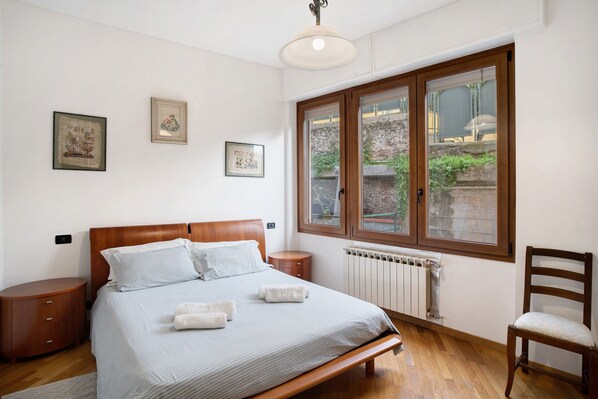 Een slaapkamer met een houten bed, nachtkastjes, een raam met uitzicht en ingelijste foto's aan de muur.