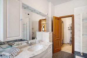 Een badkamer met een grote spiegel, een wastafel en een douchehoek.