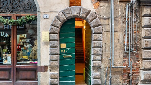A green door with a brass plaque, a stone archway, and a brick wall. - San Giorgio A Apartment - Lucca with Wi-Fi (Lucca)
