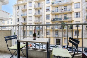 Ein Balkon mit Tisch, Stühlen, einer Flasche und einem Glas.
