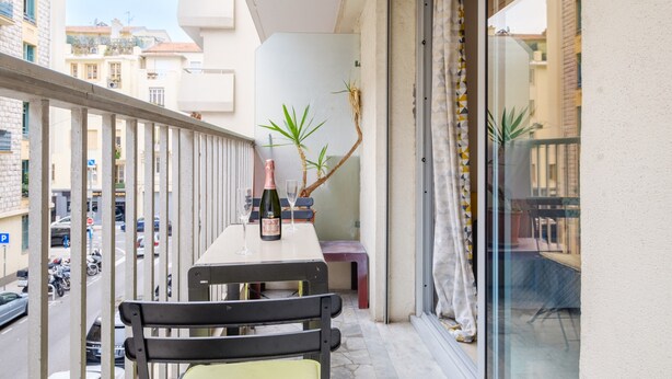 A balcony with a table, chairs, a bottle, and a glass. - Superb apartment in Nice: comfort and charm in the heart of the city (Nice)