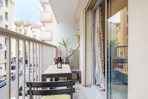 A balcony with a table, chairs, a bottle, and a glass.