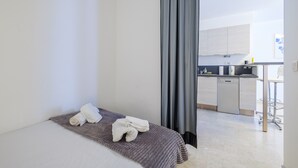 A modern hotel room with a bed, a bathroom, and a kitchenette. - Superb apartment in Nice: comfort and charm in the heart of the city (Nice)