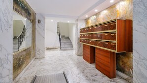 A hallway with marble flooring, a staircase, and a wooden storage unit with drawers. - Superb apartment in Nice: comfort and charm in the heart of the city (Nice)