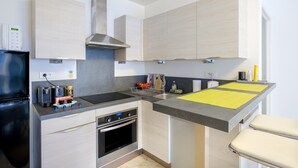 A modern kitchen with a built-in oven, a stainless steel range hood, and a grey countertop. - Superb apartment in Nice: comfort and charm in the heart of the city (Nice)