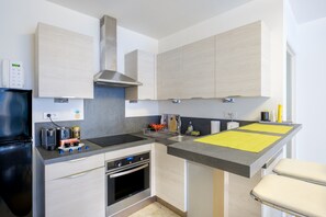 Een moderne keuken met een inbouwoven, een roestvrijstalen afzuigkap en een grijze werkblad.