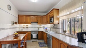 A kitchen with wooden cabinets, a microwave, a sink, and a dining table with chairs.