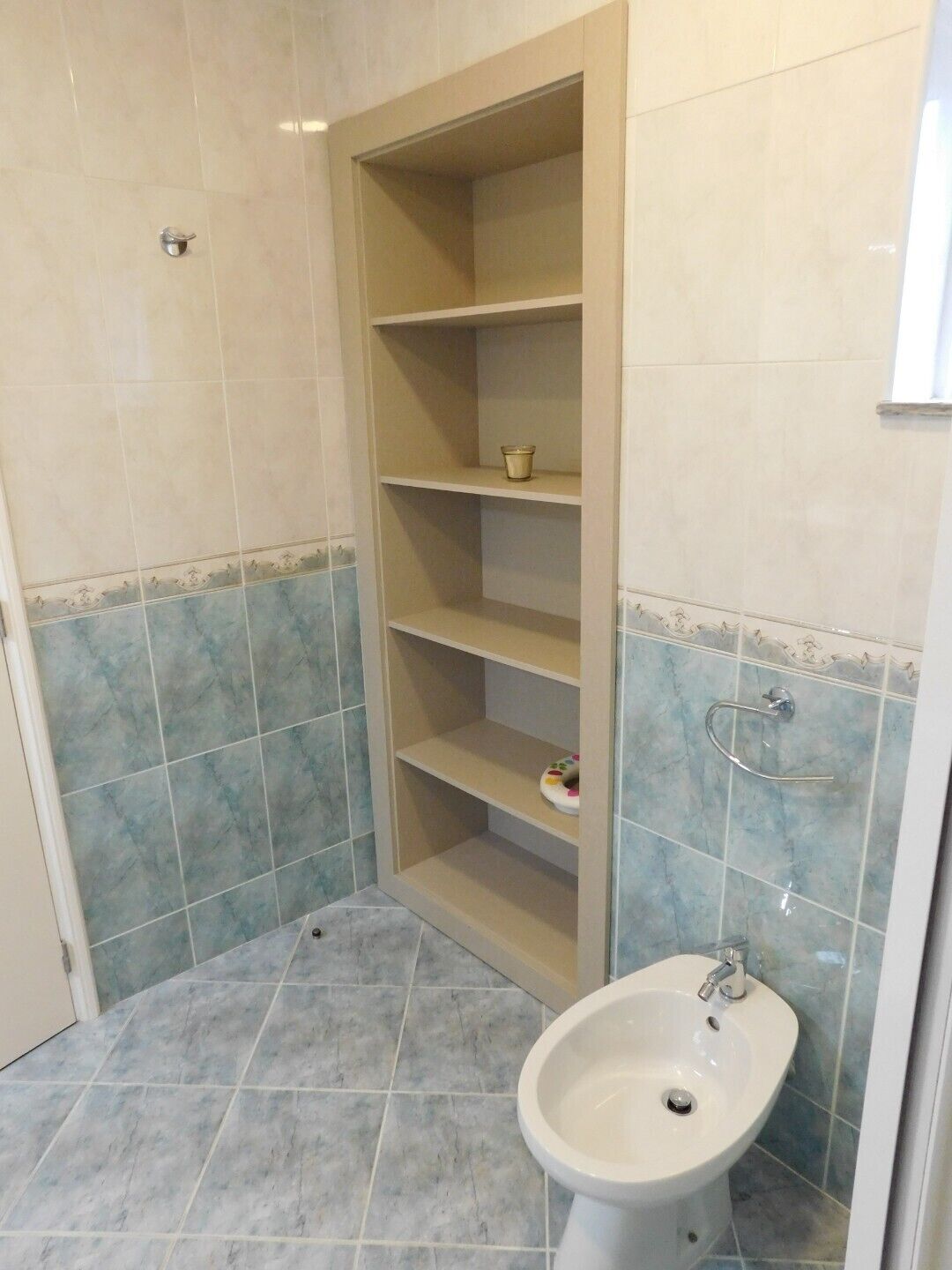 Un baño con lavamanos, estantería y zona de ducha.