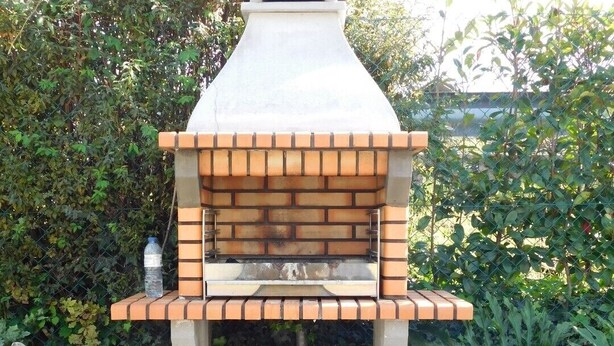 A brick-built outdoor oven with a chimney, surrounded by greenery and potted plants. - Holiday Home 'Casa Da Veiga - Natureza E Cidade' with Private Terrace, Wi-Fi and Air Conditioning (Lago)