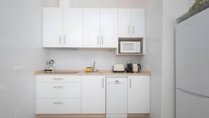 A modern kitchen with white cabinets, a microwave, a toaster, and a dishwasher.