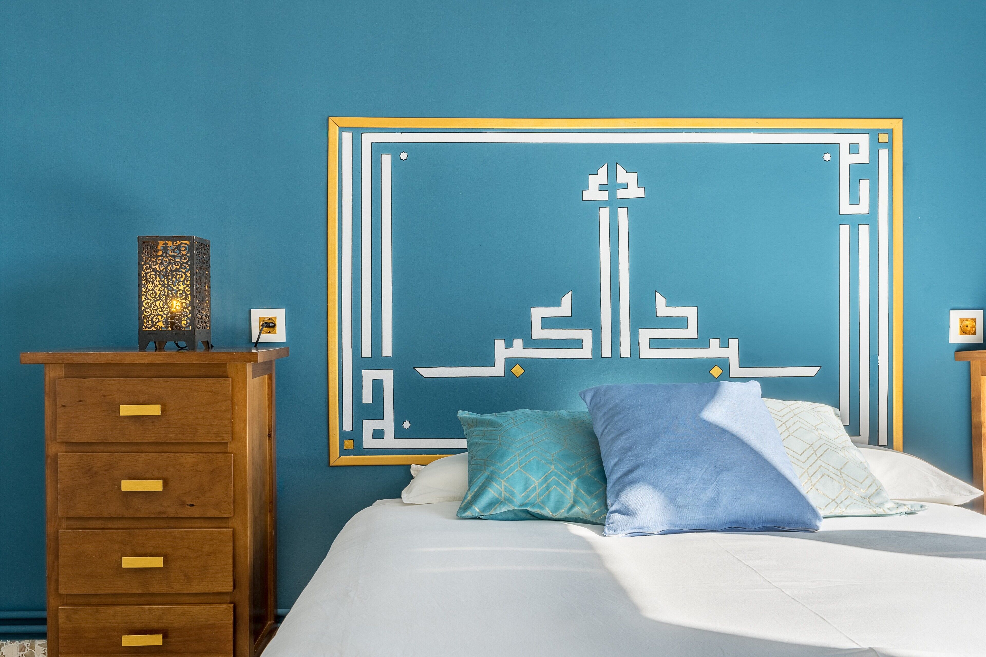 A bedroom with a bed, a dresser, a wall art piece, and a nightstand.