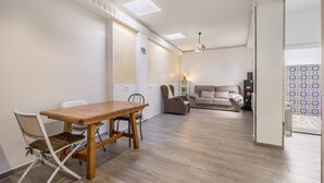 Een moderne woonkamer met een houten eettafel, een bank en een decoratieve lamp.