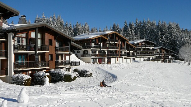 A ski resort with multi-story buildings, snow-covered trees, and a ski slope.