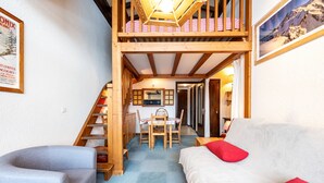 A loft-style room with a staircase, a dining area, and a sofa.
