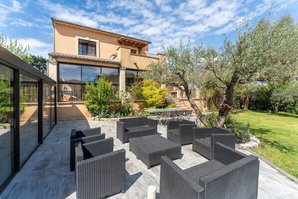 A modern house with a patio area featuring wicker furniture and a glass-enclosed section.