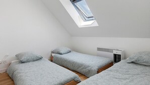 A dormitory room with two beds, a skylight, and a wall-mounted air conditioner.