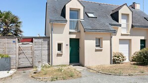 A two-story house with a green door, a small balcony, and a grey roof.