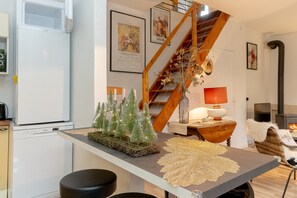 A modern kitchen with a white refrigerator, a wooden staircase, and a dining area with a table set for two.