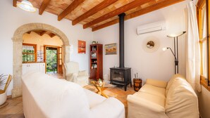 Una sala de estar con sofá, una mesa de centro de vidrio, chimenea y un arco de piedra que da a otra habitación.