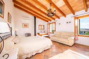 A bedroom with a bed, a sofa, a desk, and a window with a view. - Chalet 'Villa Ca'n Tabou' with Mountain View, Private Pool and Wi-Fi (Selva)