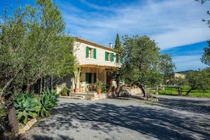 A stone house with a tiled roof, green shutters, and a gravel driveway. - Chalet 'Villa Ca'n Tabou' with Mountain View, Private Pool and Wi-Fi (Selva)