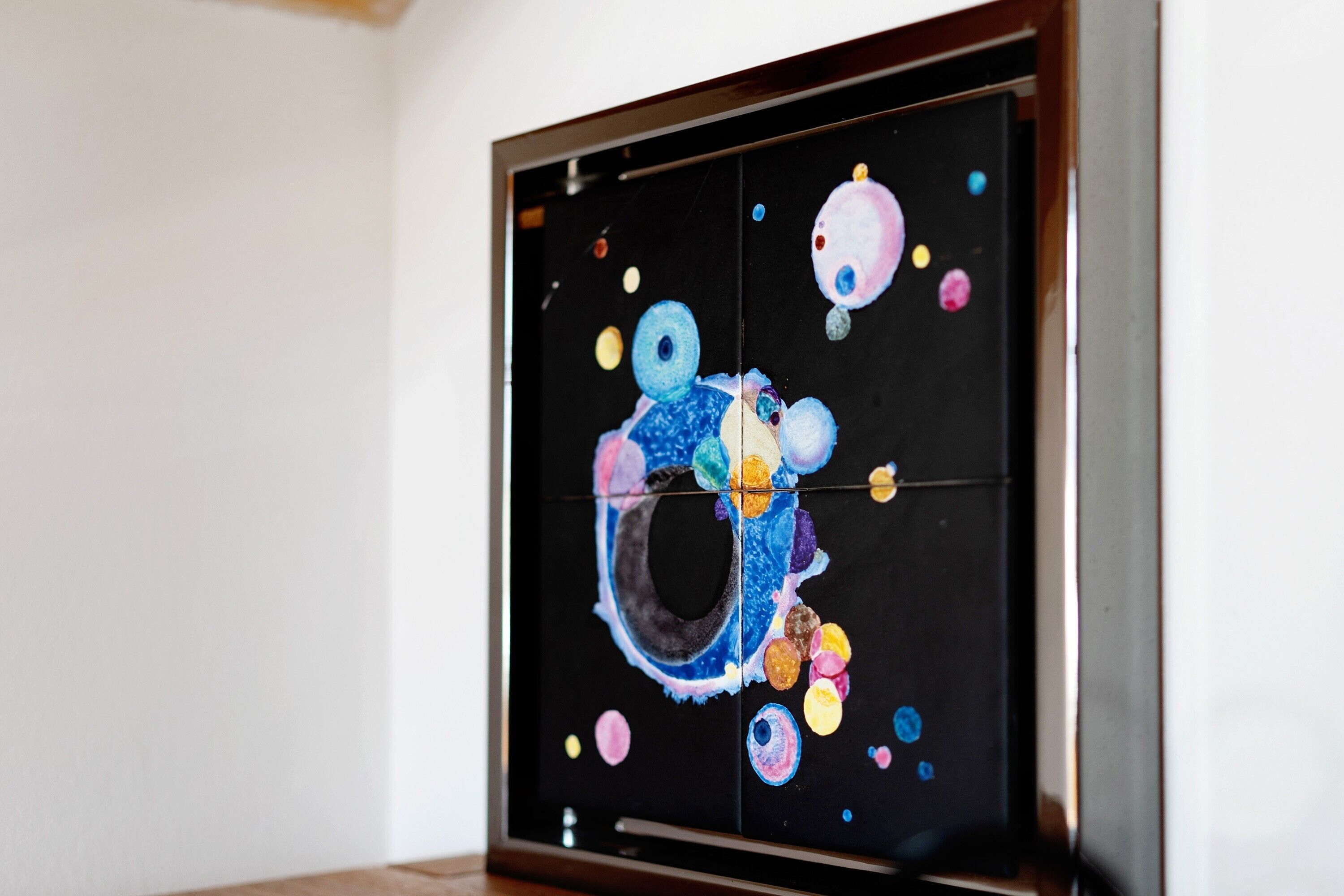 Ein gerahmtes Kunstwerk mit abstrakten Mustern und kreisförmigen Formen.