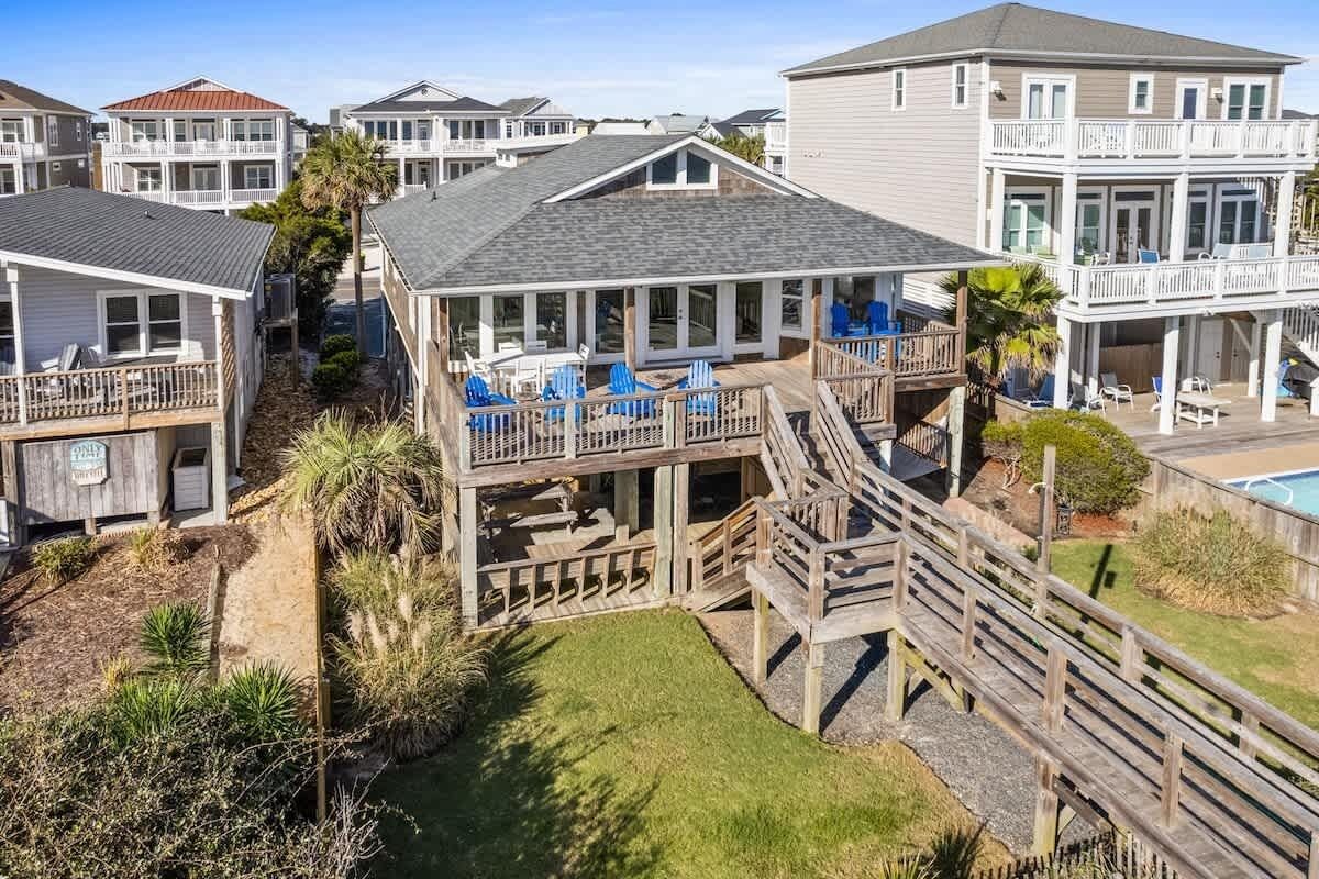 A coastal residential area with multiple houses featuring balconies, outdoor seating, and a wooden deck.