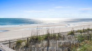 Une plage bordée d’une clôture en bois, offrant une vue dégagée sur l’océan.