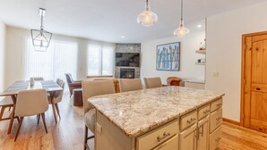 Una cocina moderna con una isla grande, armarios de madera e iluminación colgante.