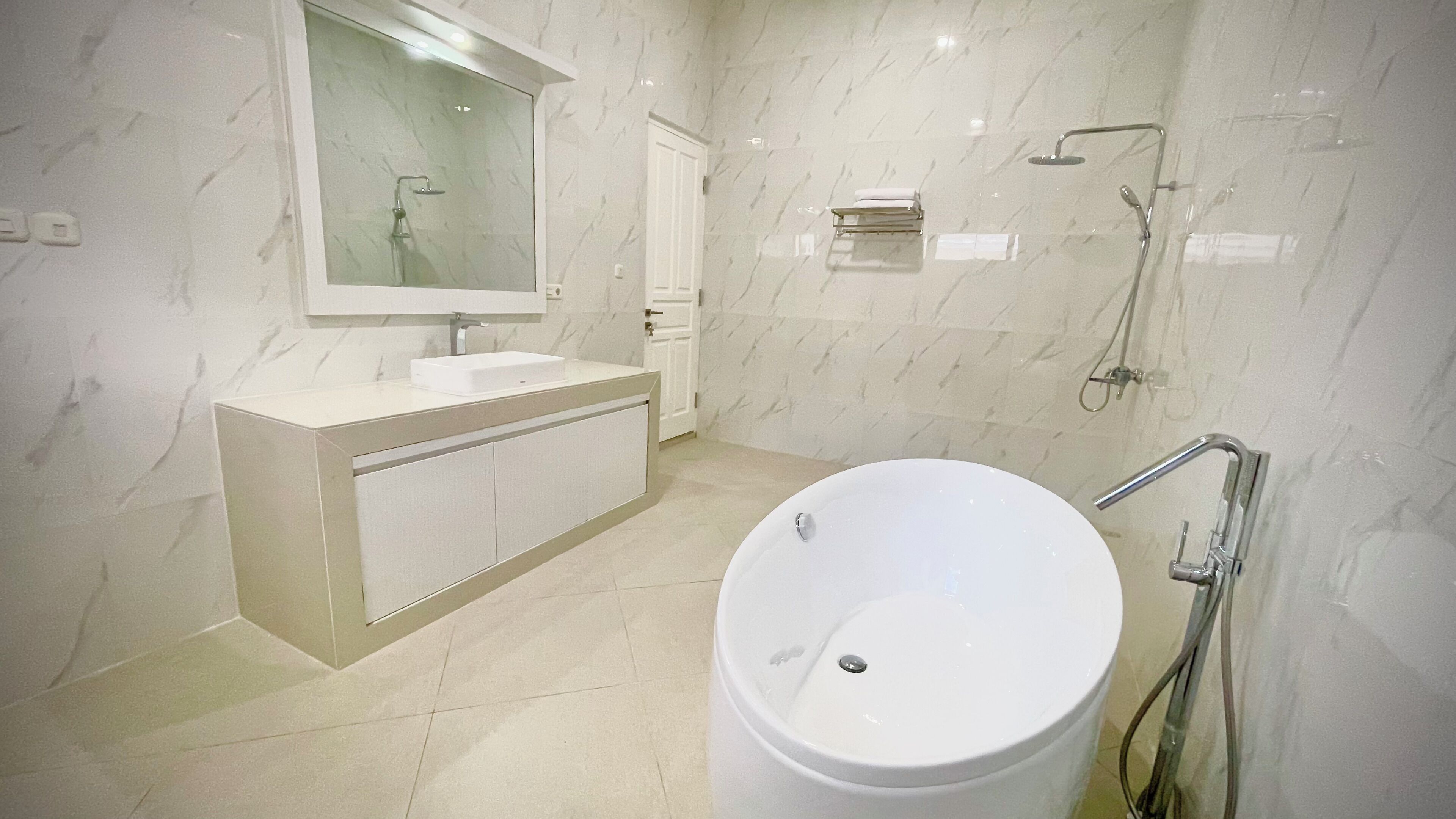 A modern bathroom with a freestanding bathtub, a large mirror, and a shower area.