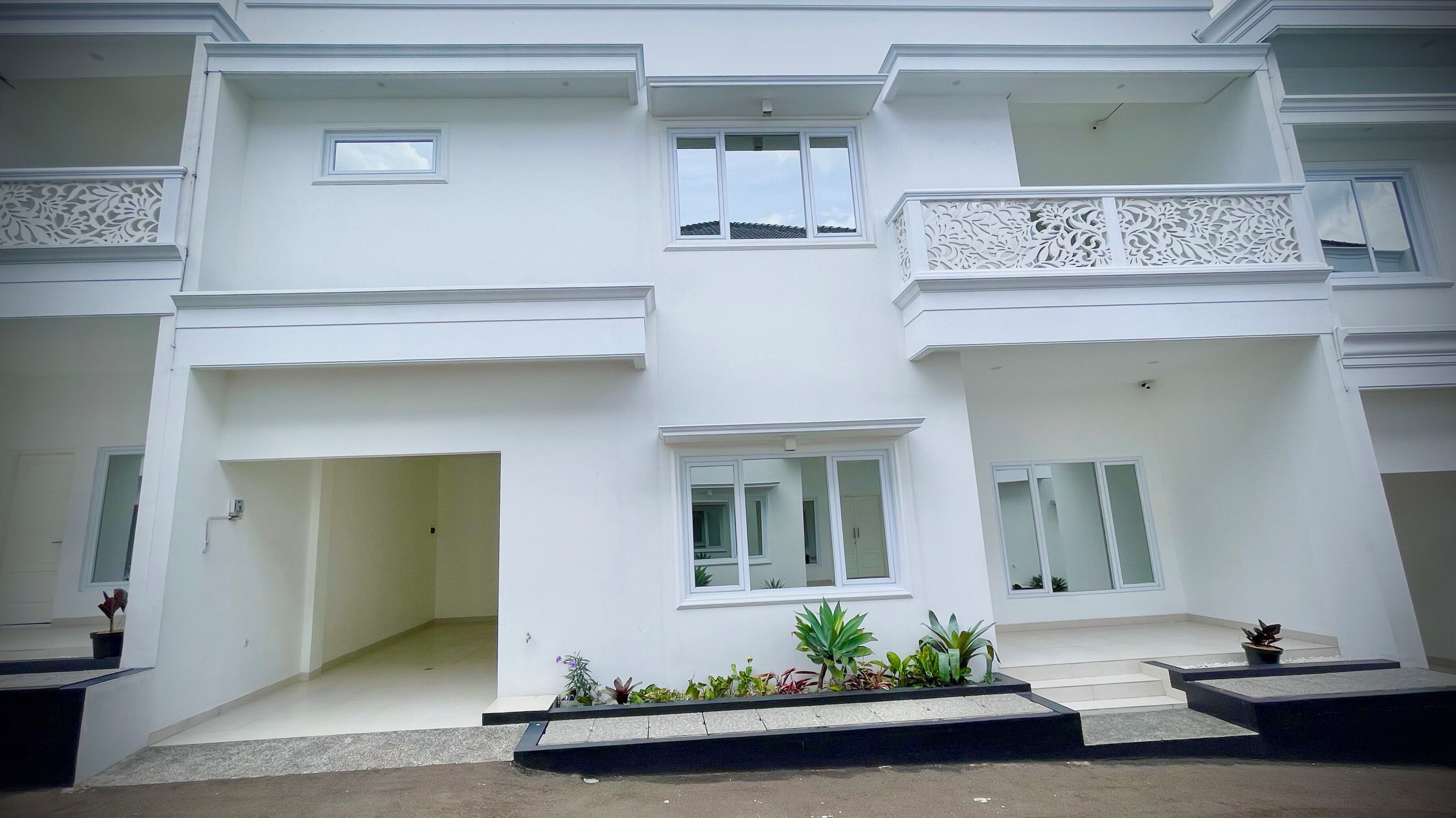 A multi-story building with white exterior walls, balconies with intricate railings, and small windows.