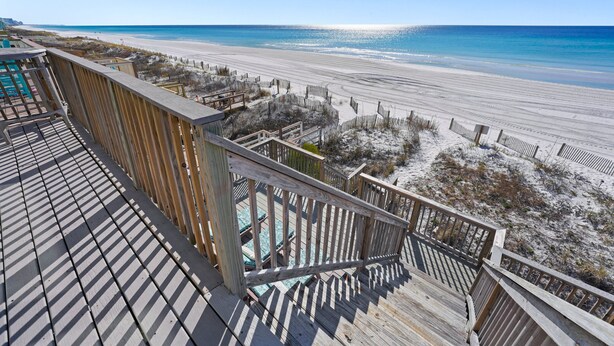 Une terrasse en bois offrant une vue sur une plage et l’océan.