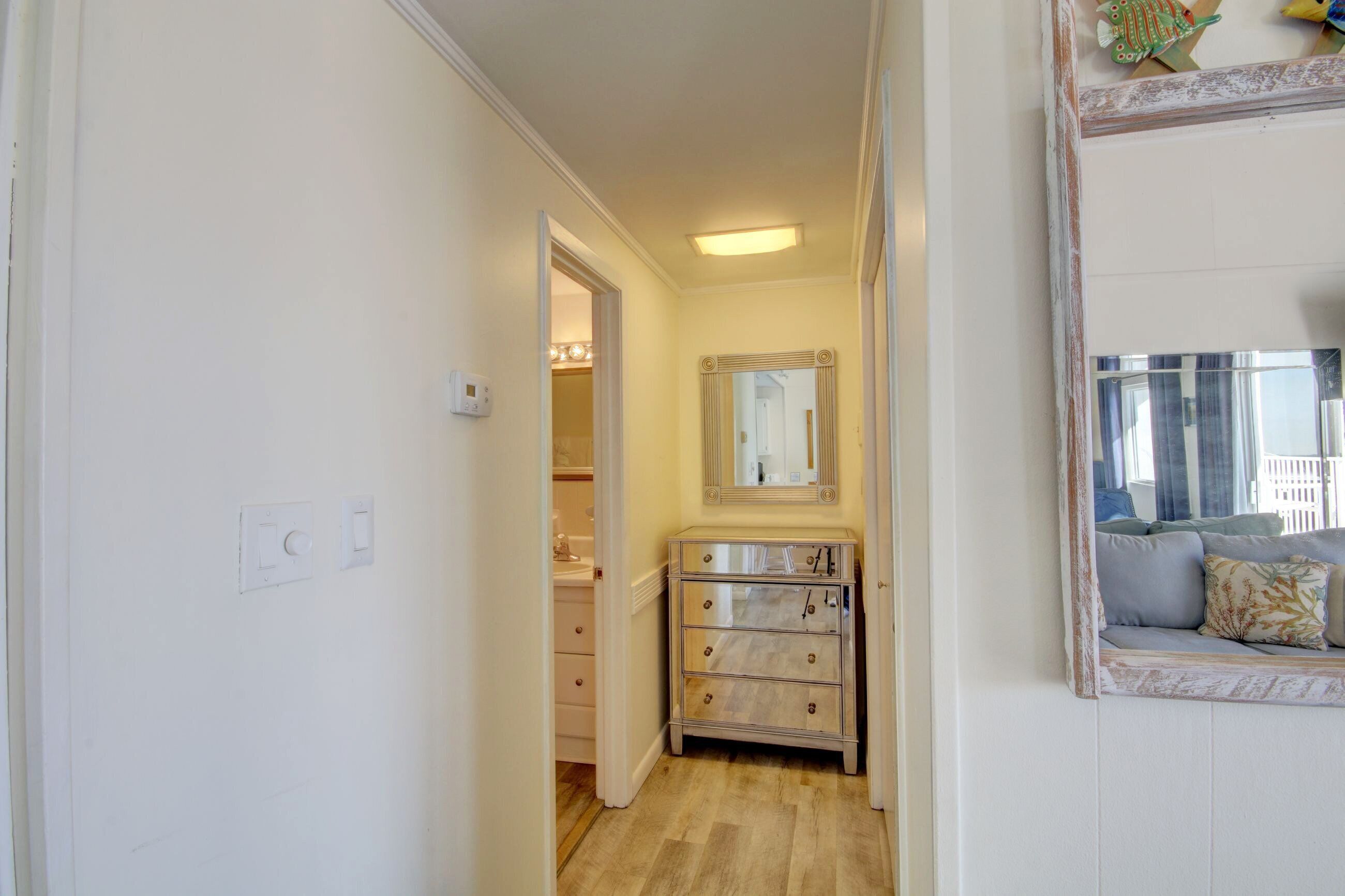 A hallway with a vanity, a mirror, and a sofa with cushions.