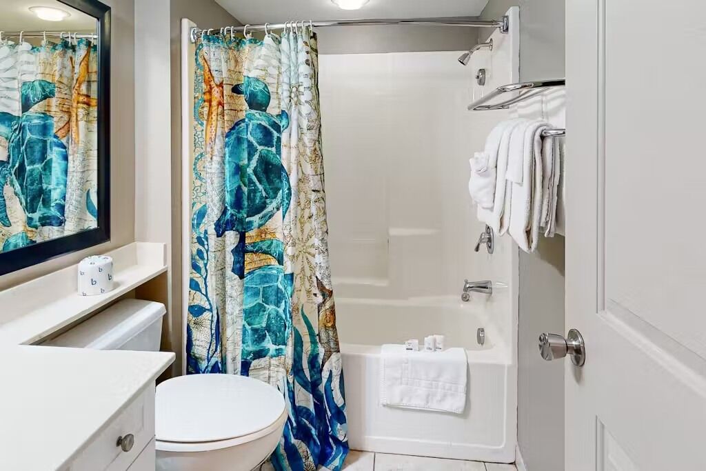 Un baño con cortina de ducha, inodoro, bañera y espejo.