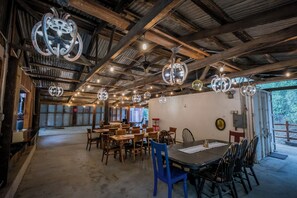 Un comedor rústico con mesas y sillas de madera, luces de bola de discoteca colgantes y vistas al exterior a través de amplios ventanales.