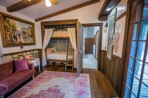 Una habitación acogedora con una cama, un sofá rojo, un tapete estampado y un cuadro en la pared.