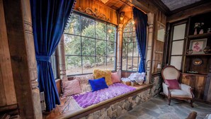 A cozy room with a stone bench, plush cushions, and a wooden chair.