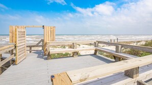 Un muelle de madera que conduce a una playa, con una estructura de madera al fondo.