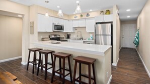 Une cuisine moderne avec des meubles blancs, des appareils en acier inoxydable et un îlot central doté de tabourets de bar.