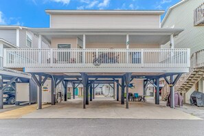 Un edificio a più piani con un balcone, un'area di parcheggio coperta e una scala ben visibile.
