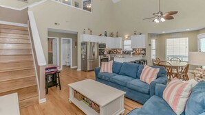 A spacious living area with a blue sofa, a white coffee table, and a kitchen in the background. - Ocean Lakes 1076 (Myrtle Beach)