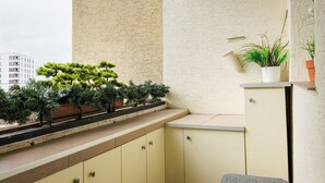 A small balcony with a built-in kitchen counter, potted plants, and a seating area. - Targówek Homely Apartment (Warszawa)
