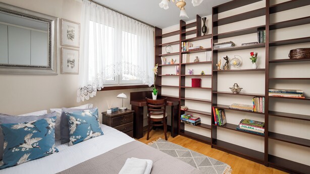 A neatly arranged bedroom with a large bed, a desk, and a bookshelf. - Targówek Homely Apartment (Warszawa)