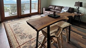 Un salón espacioso con un ventanal grande, una mesa de centro de madera, un sofá de cuero y una araña.