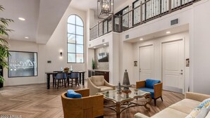 A spacious living room with a high ceiling, a dining area with a table and chairs, and a staircase leading to an upper level. - Stay longer, Spend Less, 2 Master Suites! The Cays (Chandler)