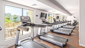 A gym with multiple treadmills aligned along a wall with large windows offering a view of palm trees and buildings. - Stay longer, Spend Less, 2 Master Suites! The Cays (Chandler)
