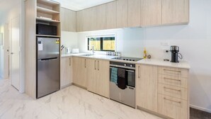 Une cuisine moderne avec des meubles en bois clair, des appareils en acier inoxydable et un sol en marbre.