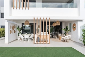 A modern two-story house with a dining area, a seating area, and a balcony.